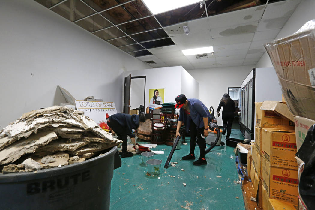 Thai restaurant Lotus of Siam staff members Brittany Edberg, left, and Sabrina Chutima, center, removes debris after a portion of its ceiling collapsed in Las Vegas, Friday, Sept. 8, 2017. Chitose ...