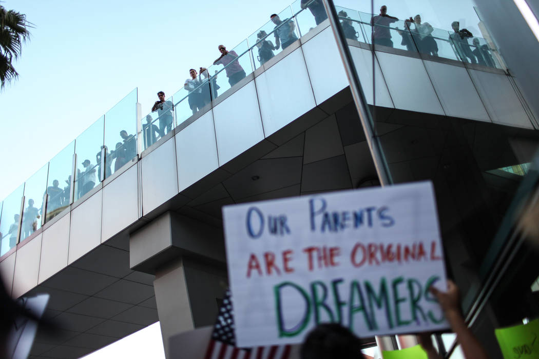 Tourists watch as several hundred DACA recipients and supporters march down the Strip in Las Vegas, Sunday, Sept. 10, 2017, to call on President Donald Trump and Nevada elected officials to protec ...