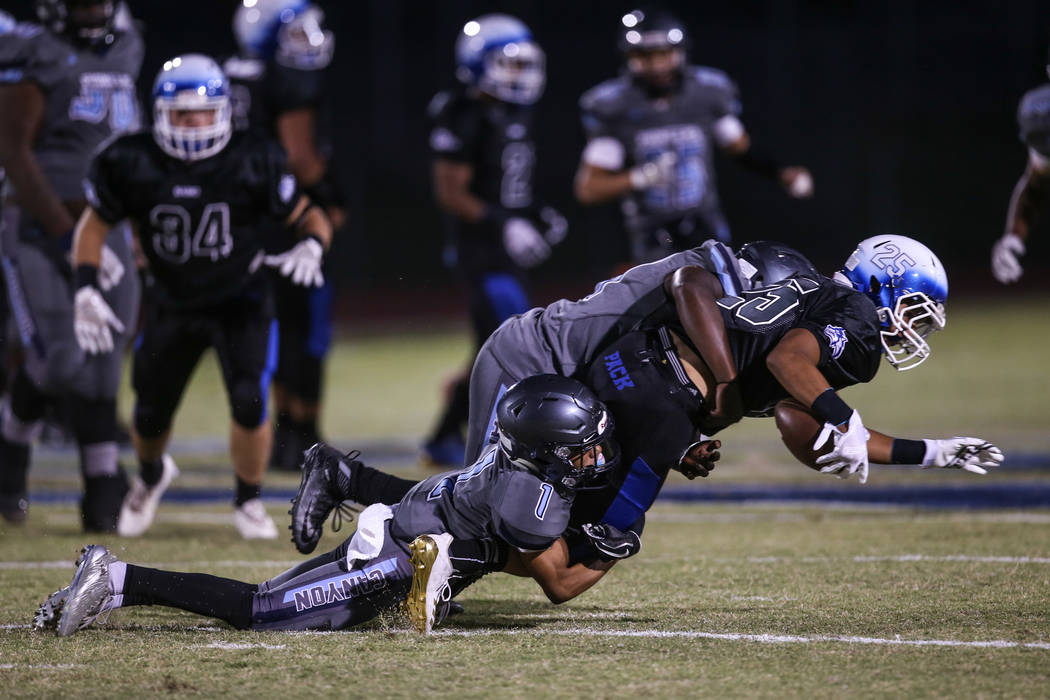 Basic's Jordan Gallegos (25) is tackled by Canyon Springs' TyՓhon Jamal-Brown (1) and Tyjohn Francis (44) during the first quarter of a football game at Basic High School in Henderson, Frida ...