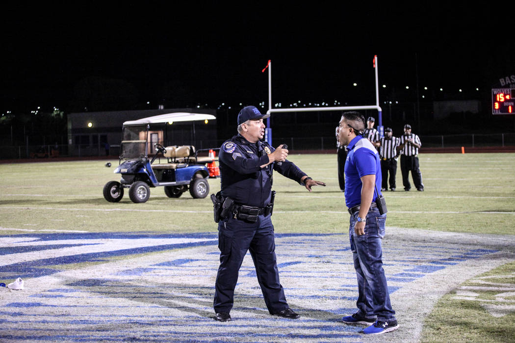 A police officer points pepper spray toward a Basic football staff after dispersing a brawl between Canyon Springs and Basic Academy's football teams at the end of a game at Basic High School in H ...