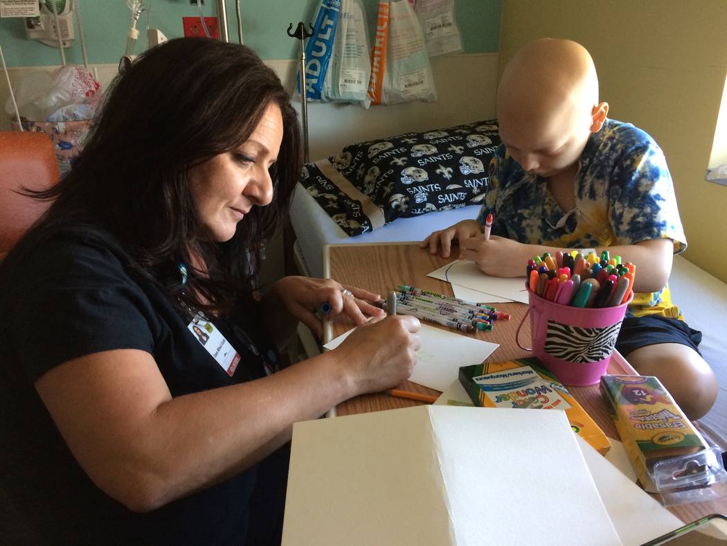 Diane Mifsud does her own art as Cole Thow, 10, works his project Aug. 18, 2017, at Summerlin Hospital. She often introduces herself the Fairy Art Princess, which brings a smile to the children’ ...