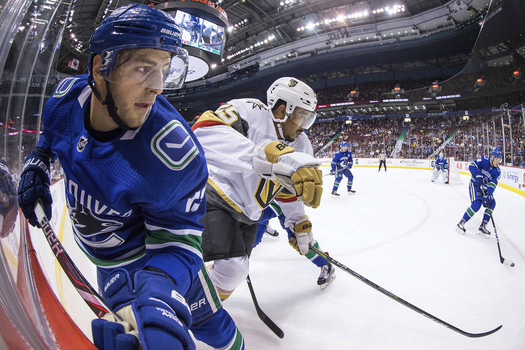 Vancouver Canucks' Griffen Molino, left, and Vegas Golden Knights' Keegan Kolesar, center, watch as Vancouver's Jaime Sifers, right, picks up the puck out of the corner during the first period of  ...