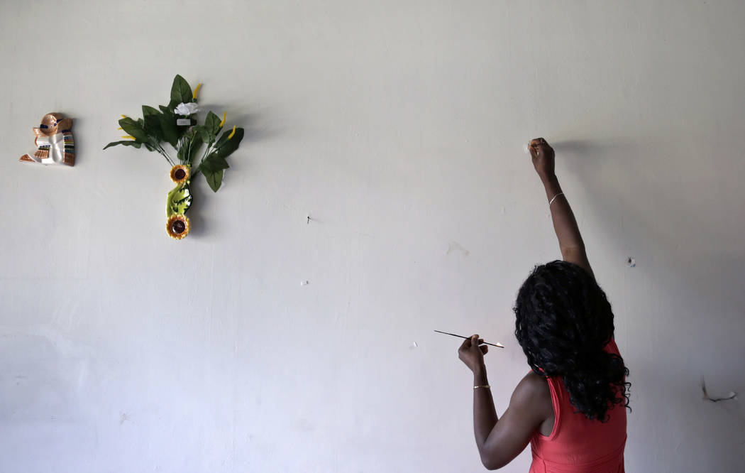 Lucy Charles, of Haiti, lights incense along a wall in her restaurant specializing in Haitian cuisine in Tijuana, Mexico, on May 24. (AP Photo/Gregory Bull)