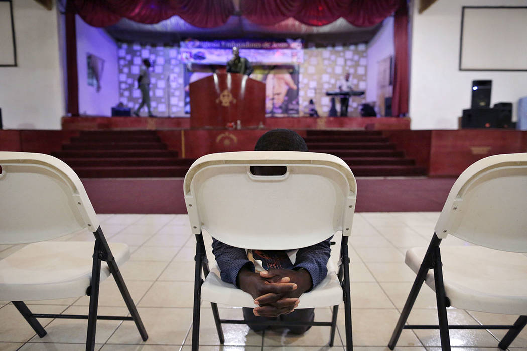 Jeccene Thimote, of Haiti, kneels in front of a folding chair in prayer during a service in Creole at The Ambassadors of Jesus Church in Tijuana, Mexico, on May 24.  (AP Photo/Gregory Bull)