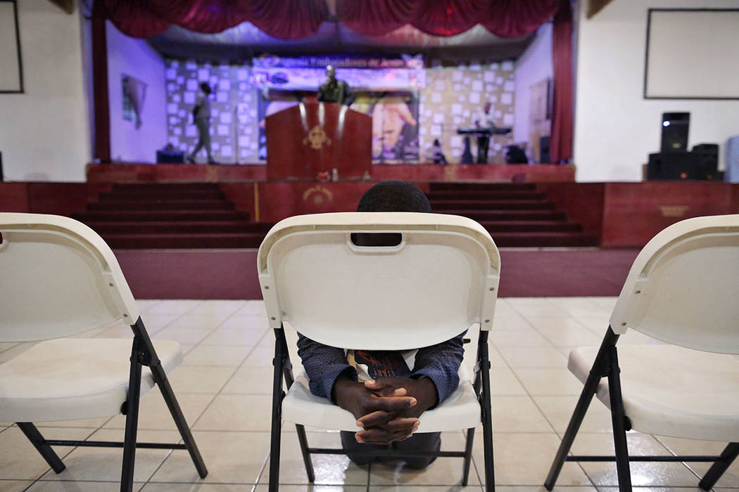 Jeccene Thimote, of Haiti, kneels in front of a folding chair in prayer during a service in Creole at The Ambassadors of Jesus Church in Tijuana, Mexico, on May 24. (AP Photo/Gregory Bull)
