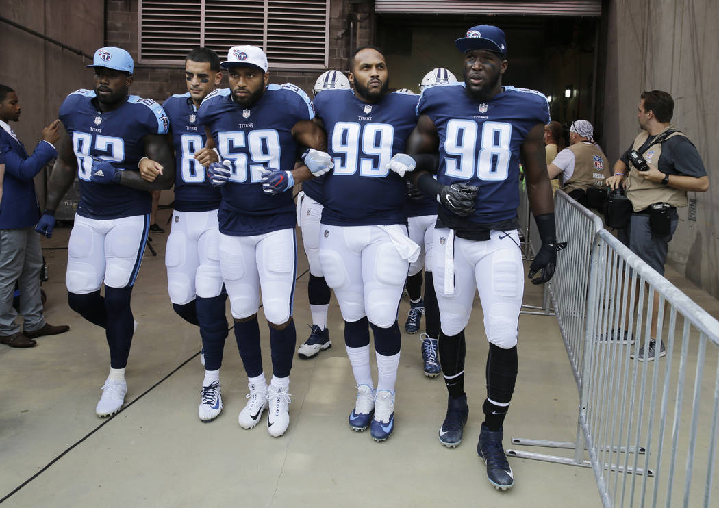Tennessee Titans players walk to the field with arms linked after the national anthem had been played before an NFL football game between the Titans and the Seattle Seahawks Sunday, Sept. 24, 2017 ...