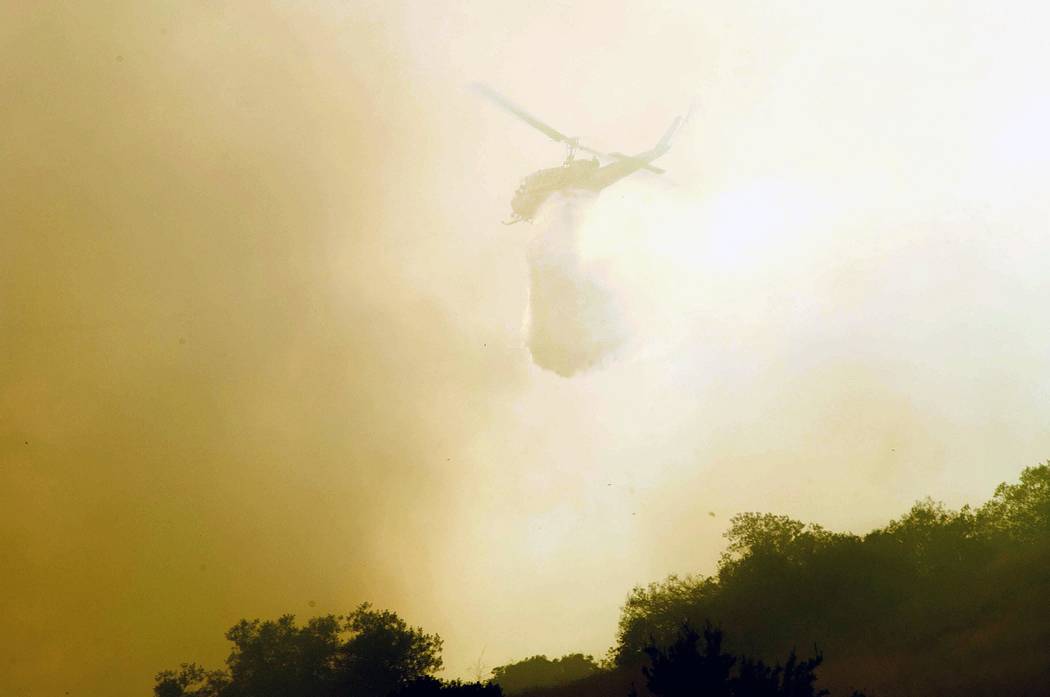 A helicopter makes a drop as a wildfire burns near State Route 91 near the Riverside County line in Anaheim Hills, Calif., Monday, Sept. 25, 2017. (Ken Steinhardt/The Orange County Register via AP)