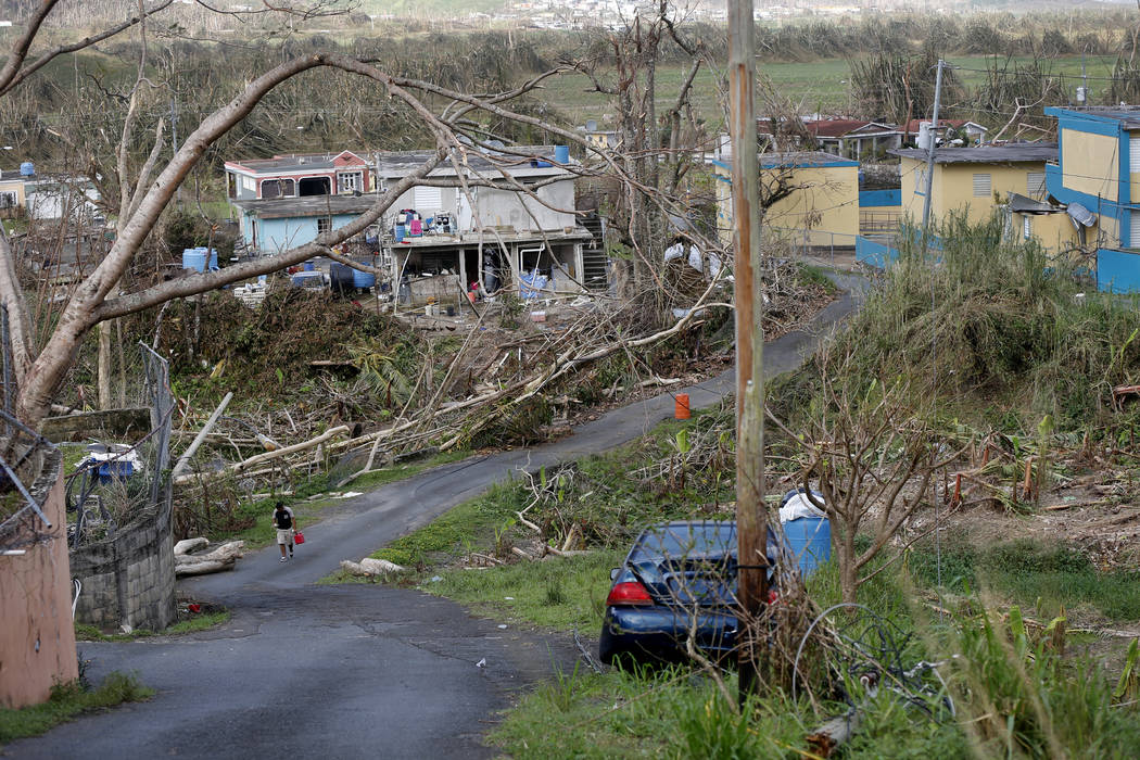 Jonathan Aponte walks with a gas can up the road to his home in the aftermath of Hurricane Maria, in Yabucoa, Puerto Rico, Tuesday, Sept. 26, 2017. President Donald Trump plans to visit Puerto Ric ...