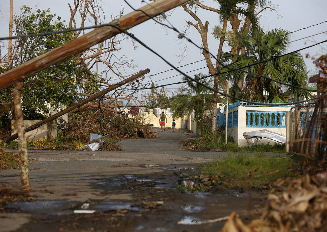 A man and child walk down street strewn with debris and downed power lines in the aftermath of Hurricane Maria, in Yabucoa, Puerto Rico, Tuesday, Sept. 26, 2017. (Gerald Herbert/AP)