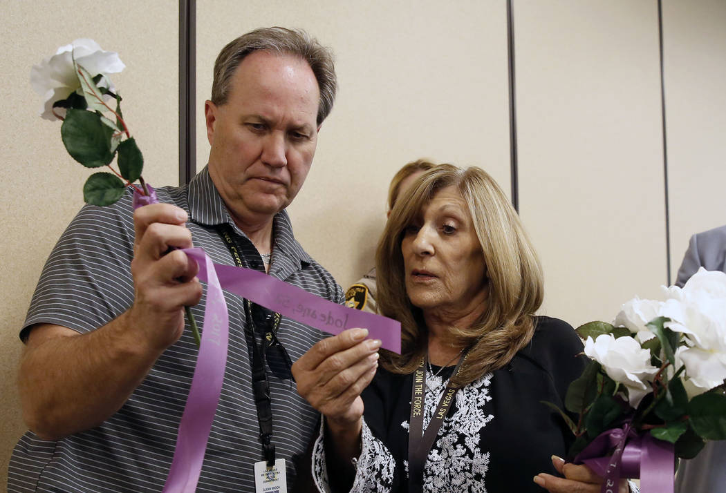 Officer Glenn Brook of the Metropolitan Police Department and Peggy Wellman of Metro's victim services read a name of a domestic violence victim on a ribbon at Metro's headquarters in Las Vegas on ...