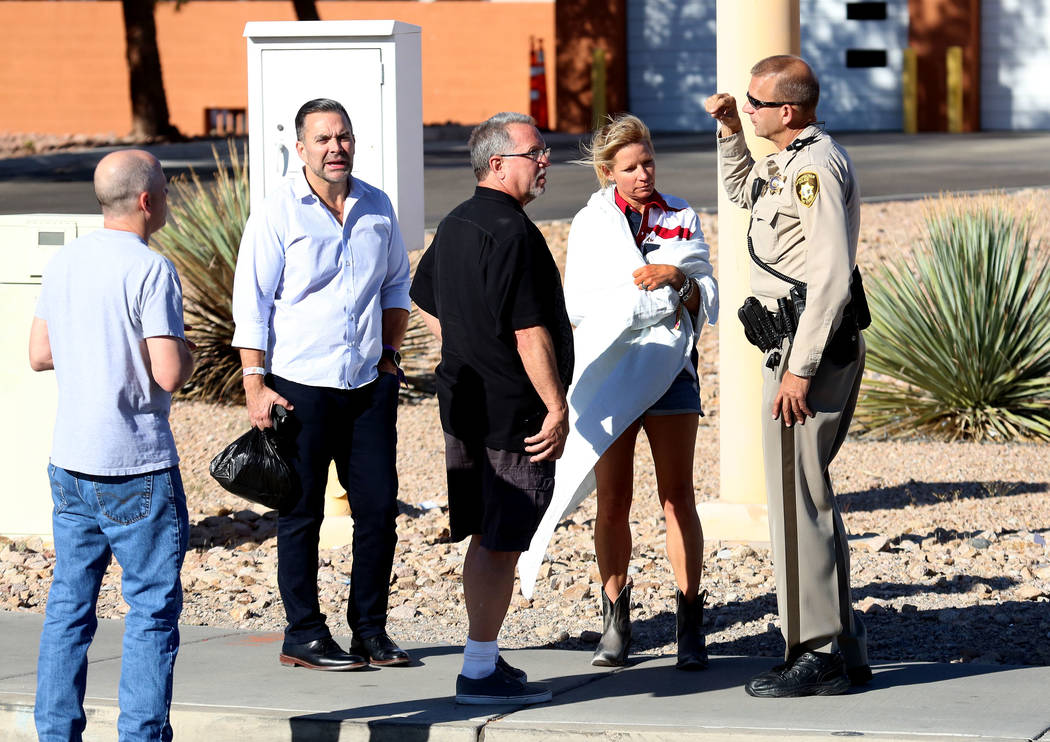 Hotel guests, including Kathy Boggio-Mocnik and her husband Gary, second left, both of Aliso Viejo, Calif., talk to a Metro police officer as they return to Mandalay Bay hotel-casino on Monday, Oc ...