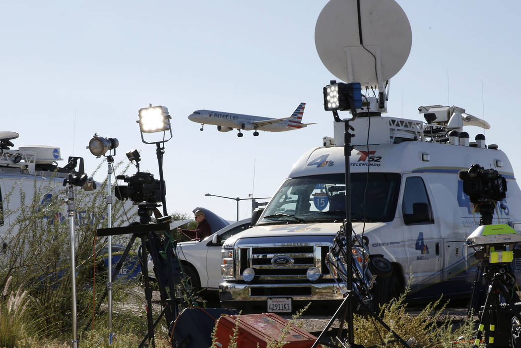 An American Airways plane flies over TV satellite trucks near McCarran International Airport on Monday, Oct. 2, 2017, in Las Vegas. Bizuayehu Tesfaye Las Vegas Review-Journal @bizutesfaye