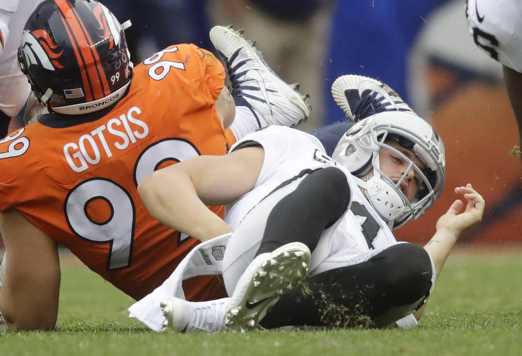 Oakland Raiders quarterback Derek Carr grabs his back after being sacked by Denver Broncos defensive ends Adam Gotsis during the second half of an NFL football game Sunday, Oct. 1, 2017, in Denver ...
