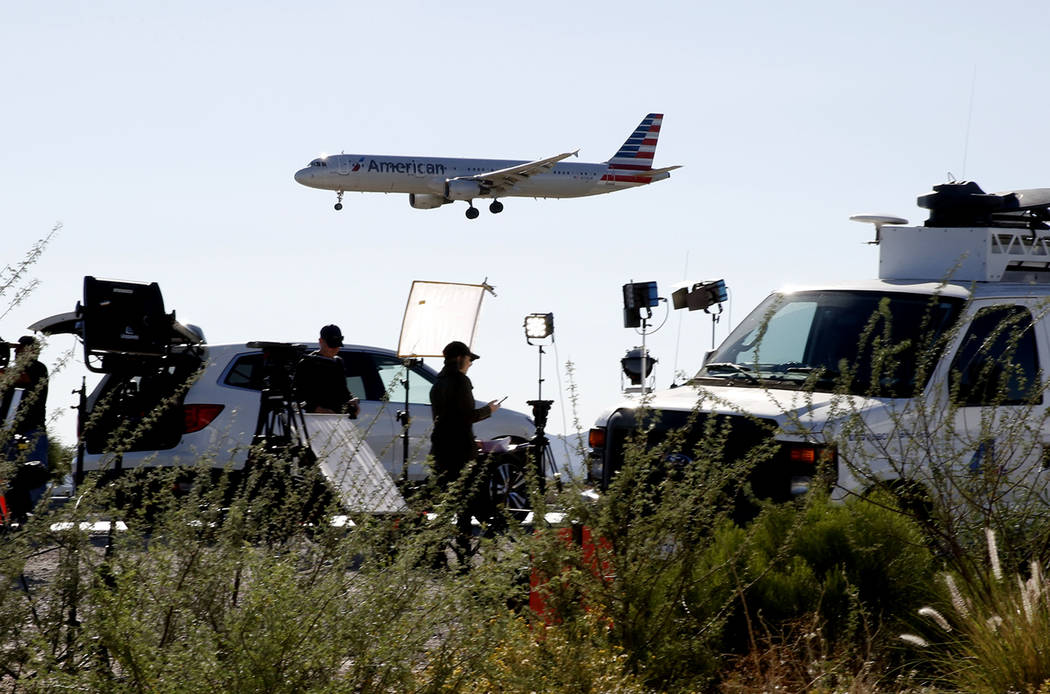 An American Airways plane flies over TV satellite trucks near McCarran International Airport on Monday, Oct. 2, 2017, in Las Vegas. Bizuayehu Tesfaye Las Vegas Review-Journal @bizutesfaye