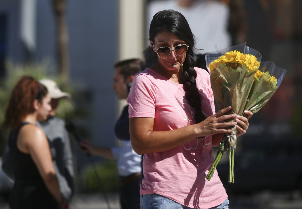 Jessica Yerkey of Ramona, Calif., who was at the Route 91 festival on Sunday, brings flowers to leave at a memorial at Las Vegas Boulevard and Sahara Avenue in Las Vegas during the early hours of  ...