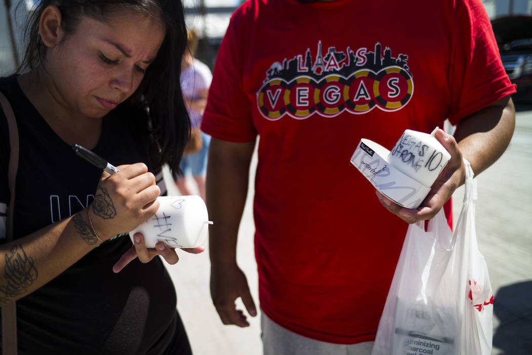 Las Vegas residents Elba Armendariz, left and David Robles prepare candles to leave at a memorial at Las Vegas Boulevard and Sahara Avenue in Las Vegas during the early hours of Tuesday, Oct. 3, 2 ...
