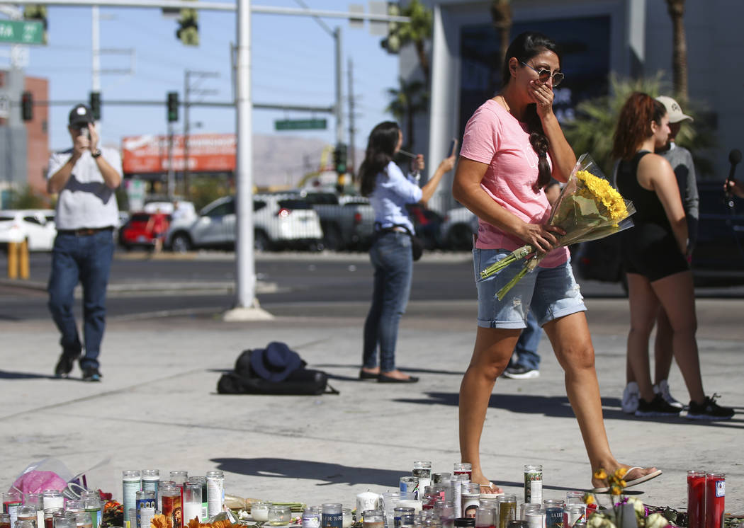 Jessica Yerkey of Ramona, Calif., who was at the Route 91 festival on Sunday, brings flowers to leave at a memorial at Las Vegas Boulevard and Sahara Avenue in Las Vegas during the early hours of  ...