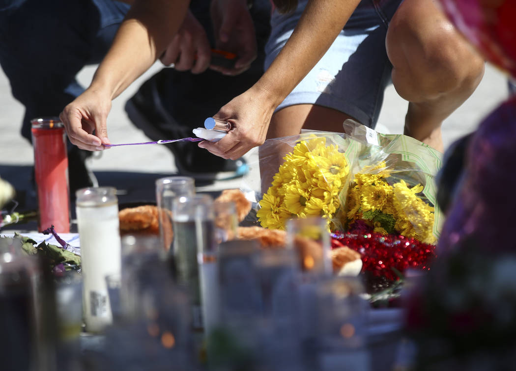 Jessica Yerkey of Ramona, Calif., who was at the Route 91 festival on Sunday, leaves her festival wristband behind at a memorial at Las Vegas Boulevard and Sahara Avenue in Las Vegas during the ea ...