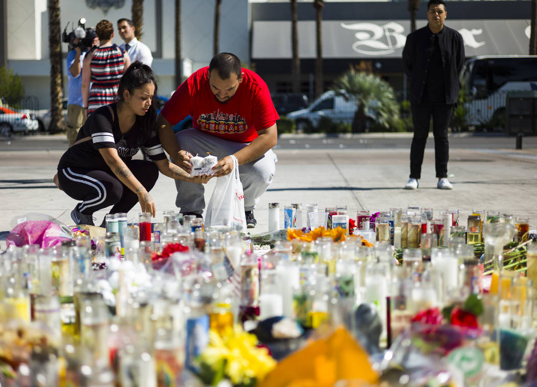 Las Vegas residents Elba Armendariz, left and David Robles light candles to leave at a memorial at Las Vegas Boulevard and Sahara Avenue in Las Vegas during the early hours of Tuesday, Oct. 3, 201 ...