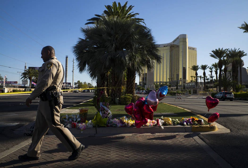 A Las Vegas police officer walks by a memorial at Las Vegas Boulevard and Reno Avenue outside of the Luxor, near the Route 91 music festival grounds in Las Vegas on Tuesday, Oct. 3, 2017. A gunman ...