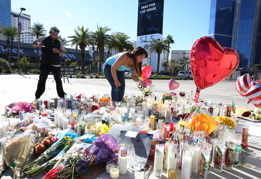 Matthew Edwards, left, and Sharine Ramos light candles on Tuesday, Oct. 3, 2017 at a makeshift memorial for the shooting victims at the corner of Sahara Avenue and Las Vegas Boulevard in Las Vegas ...