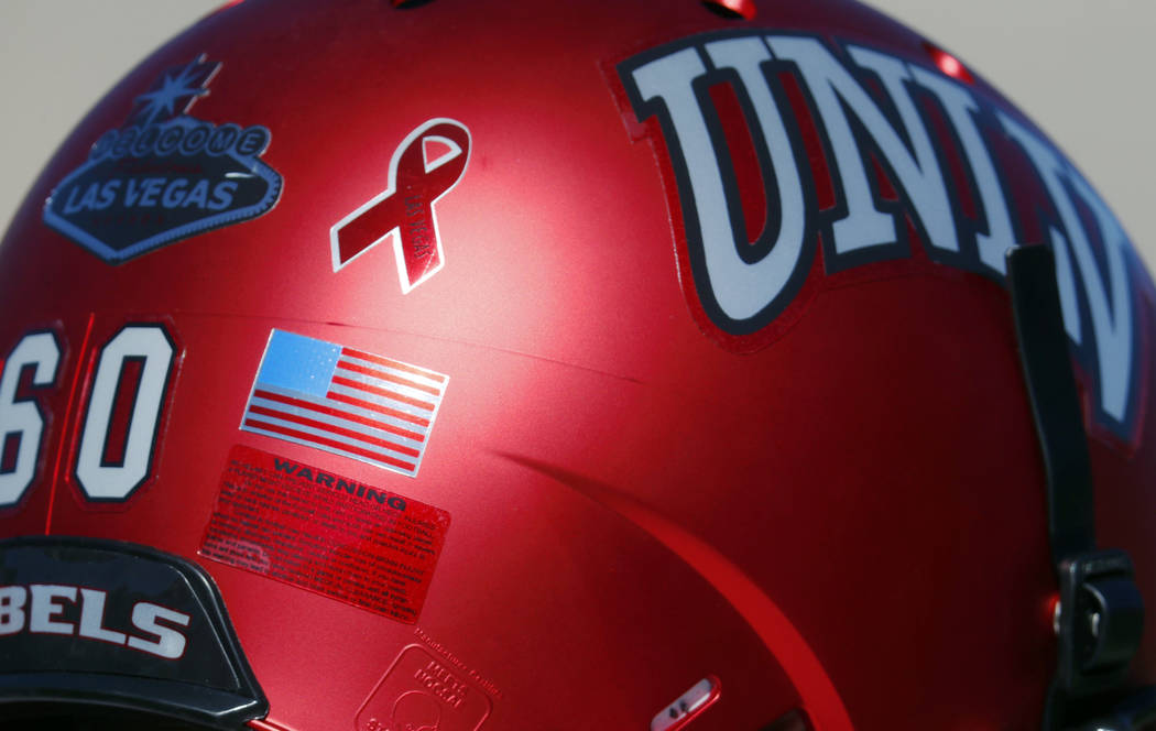 A ribbon inscribed with the words Las Vegas is illuminated on the back of the helmet of UNLV offensive lineman Andrew Erbes to commemorate the victims of the shooting massacre, as players warm up  ...