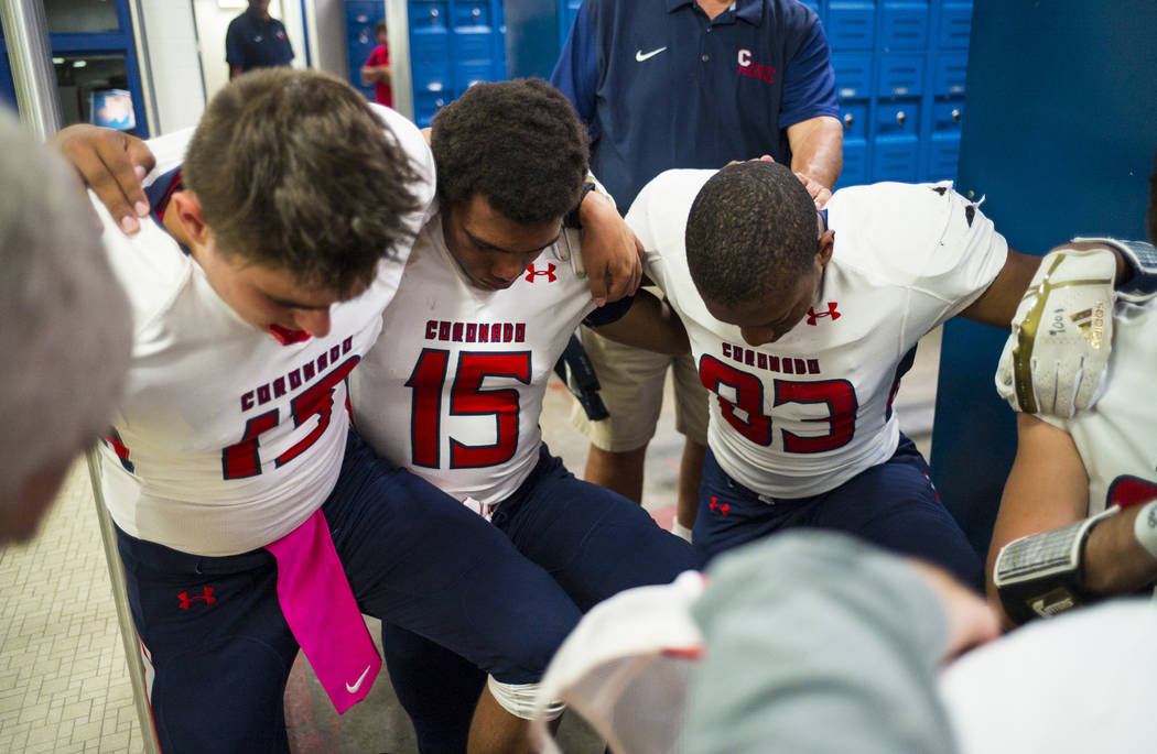Coronado's Ayzayah Hartfield (15), son of fallen Las Vegas police officer Charleston Hartfield, huddles with teammates for a prayer in the locker room before a football game at Basic High School i ...