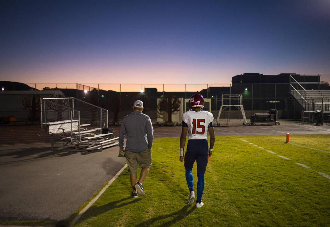 Coronado head coach William Froman, left, walks with Coronado's Ayzayah Hartfield (15), son of fallen Las Vegas police officer Charleston Hartfield, before a football game at Basic High School in ...