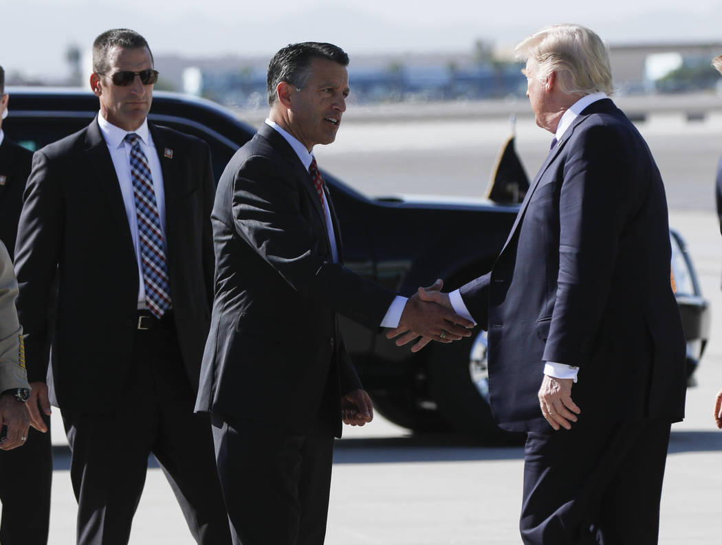 Gov. Brian Sandoval, left, greets President Donald Trump upon his arrival at McCarran International Airport in Las Vegas on Wednesday, Oct. 4, 2017. A gunman opened fire on attendees of a music fe ...