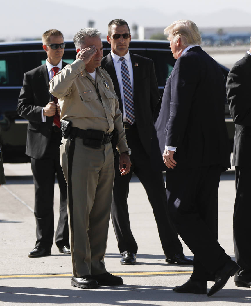 Clark County Sheriff Joe Lombardo, left, salutes as President Donald Trump arrives at McCarran International Airport in Las Vegas on Wednesday, Oct. 4, 2017. A gunman opened fire on attendees of a ...