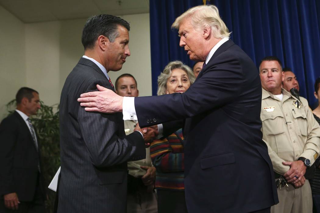 President Donald Trump embraces Nevada Gov. Brian Sandoval at Metropolitan Police Department headquarters in Las Vegas on Wednesday, Oct. 4, 2017. A gunman opened fire on attendees of a music fest ...