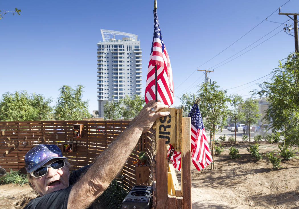 Las Vegas resident Michael James Smith, 66, puts a U.S. flag on the prayer wall as he volunteers at an under-construction community healing garden located at South Casino Center and East Charlesto ...