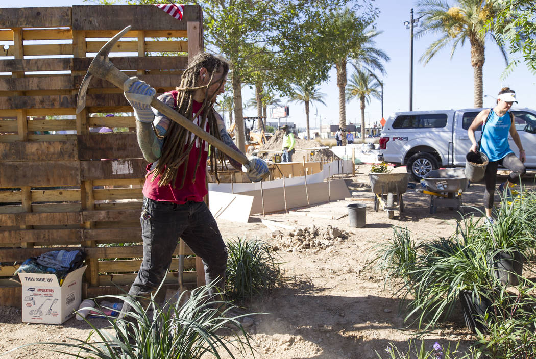 Las Vegas native Kelly Zurowski, 26, throws a pick as he volunteers at an under-construction community healing garden located at South Casino Center and East Charleston boulevards in downtown Las  ...