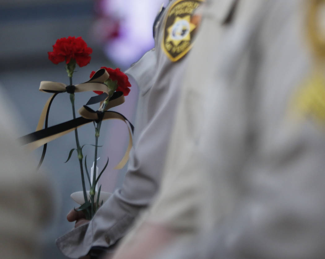 Las Vegas police officers hold roses during a candlelight vigil for Las Vegas police officer Charleston Hartfield, who was killed while off-duty in Sunday's mass shooting, at Police Memorial Park  ...
