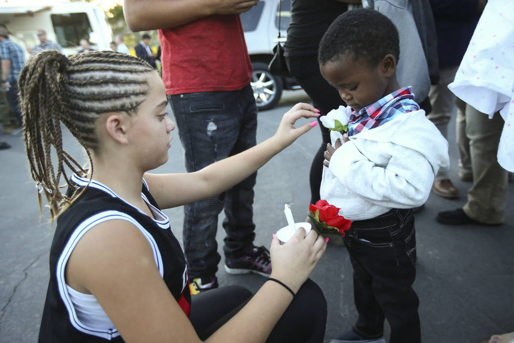 Twelve-year-old Mariah Bailor, a cousin of fallen Las Vegas police officer Charleston Hartfield, who was killed while off-duty in Sunday's mass shooting, puts a rose on Samajay Louis, 3, during a  ...