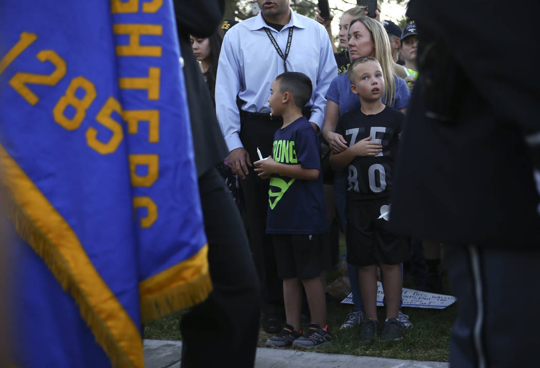 Attendees watch as the Honor Guard passes by during a candlelight vigil for Las Vegas police officer Charleston Hartfield, who was killed while off-duty in Sunday's mass shooting, at Police Memori ...