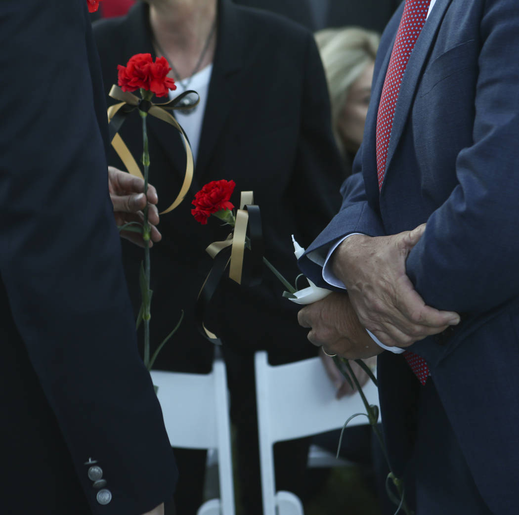 U.S. Rep. Ruben Kihuen, D-Nev., and Nevada Lt. Gov. Mark Hutchison hold roses during a candlelight vigil for Las Vegas police officer Charleston Hartfield, who was killed while off-duty in Sunday' ...