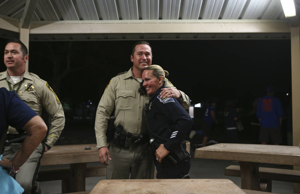 Las Vegas police officer Casey Clarkson, center, hugs a friend after a candlelight vigil for fellow officer Charleston Hartfield, who was killed while off-duty in Sunday's mass shooting, at Police ...
