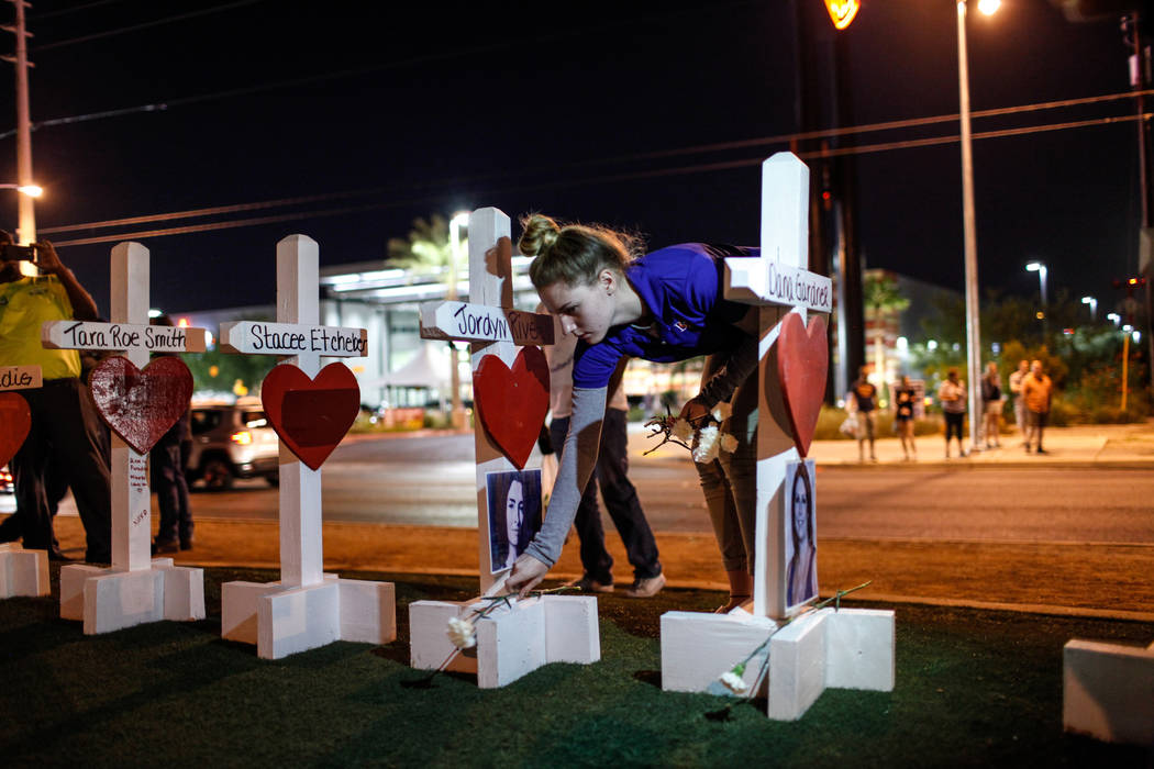 Victoria Karp of Las Vegas and student at Bishop Gorman, 17, places flowers at crosses honoring the victims of Sunday night's shooting during a vigil at the Welcome to Fabulous Las Vegas sign in L ...