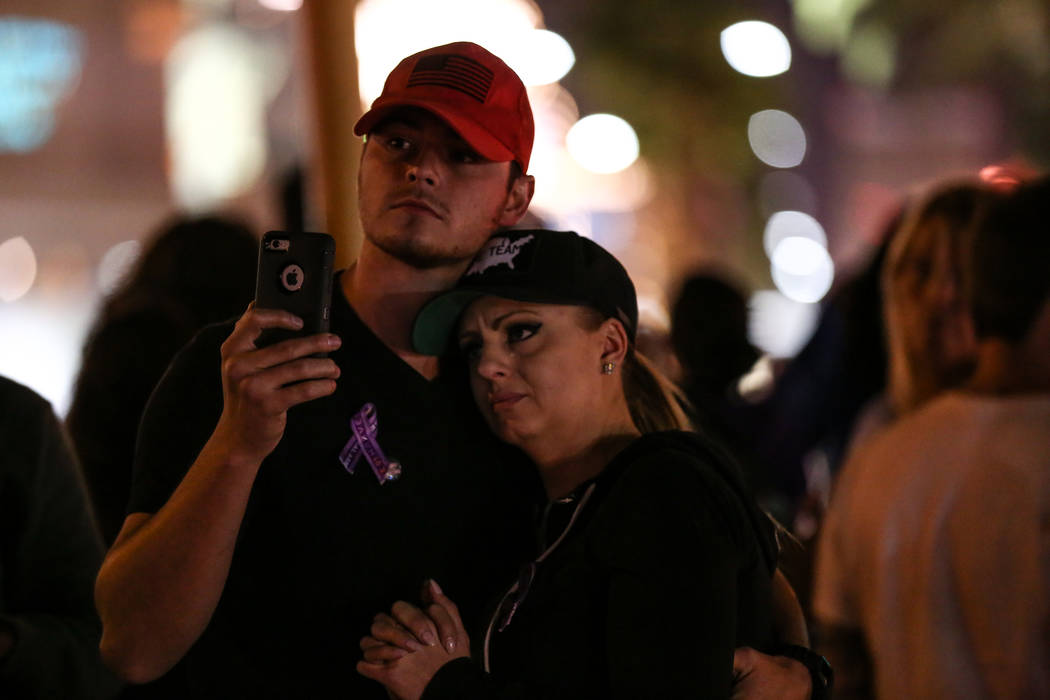 Andrew Fusaro, 23, left, and Kristy-Marie Hoff, 32, right, both of Las Vegas, hug as some lights along the Strip turned off at 10:05 p.m. for 11 minutes marking exactly one week after the mass sho ...
