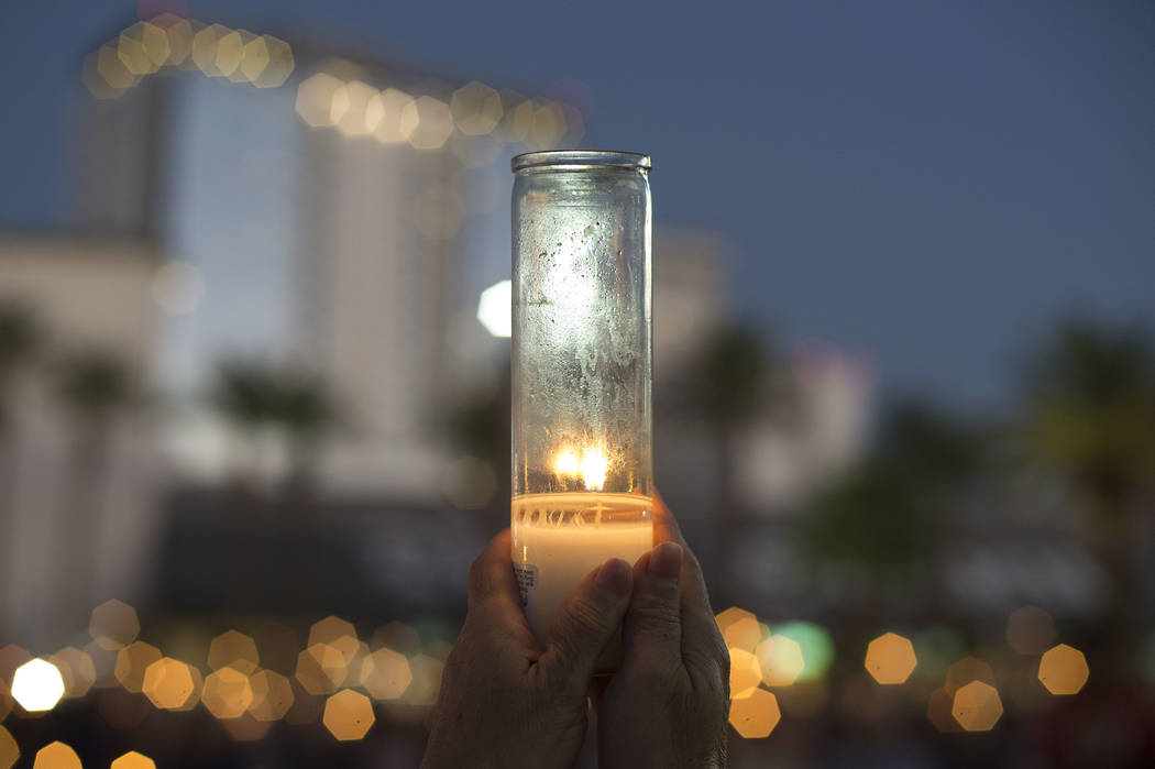 Attendees raise candles during a vigil in honor of the victims exactly one week after the mass shooting on Oct. 1, 2017, on the corner of Sahara Avenue and Las Vegas Boulevard in Las Vegas, Sunday ...