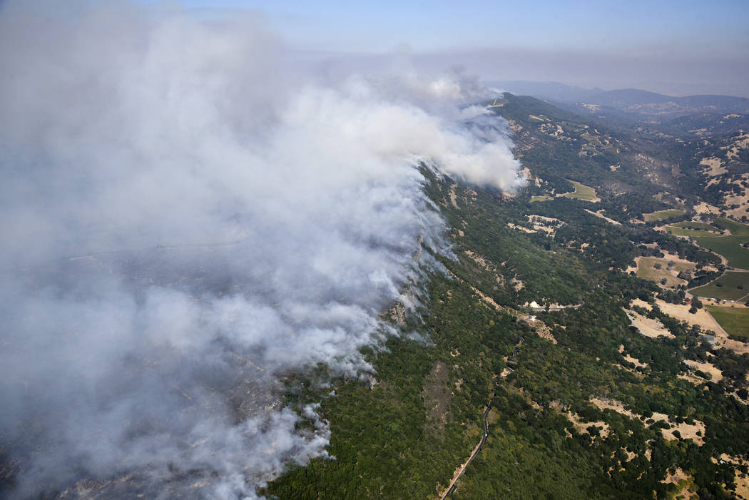 Smoke rises as a wildfire burns in the hills east of Napa, Calif., Monday, Oct. 9, 2017. Wildfires whipped by powerful winds swept through Northern California sending residents on a headlong fligh ...