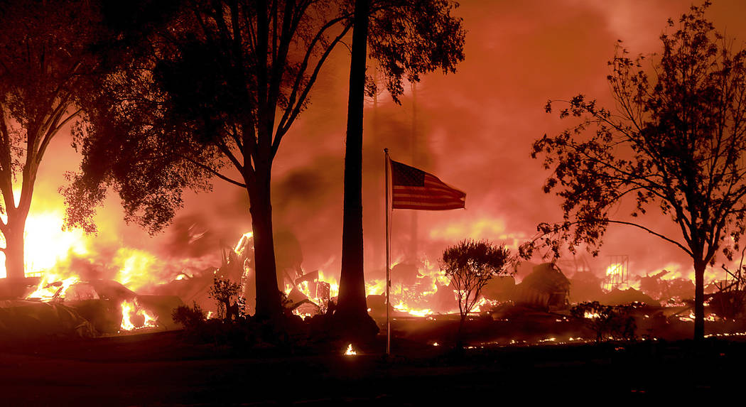 An American flag still fly's as as structures burn in Coffey Park, Monday Oct. 9, 2017. More than a dozen wildfires whipped by powerful winds been burning though California wine country. The flame ...