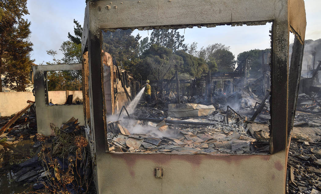 A firefighter puts out hot spots in a home that was destroyed by a wildfire in Anaheim Hills in Anaheim, Calif., Monday, Oct. 9, 2017. (Jeff Gritchen/The Orange County Register via AP)