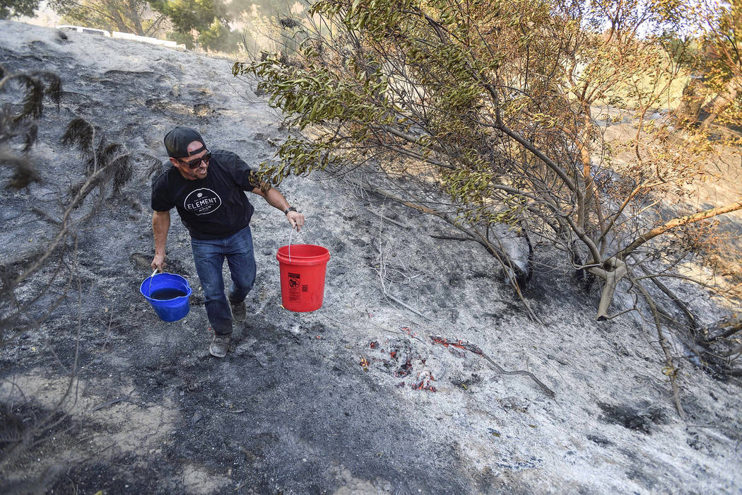 Brandon Zimprich looks for hot spots as he walks along the hillside off East Avenida de Santiago in Anaheim, Calif., Monday, Oct. 9, 2017. Wildfires whipped by powerful winds swept through Norther ...