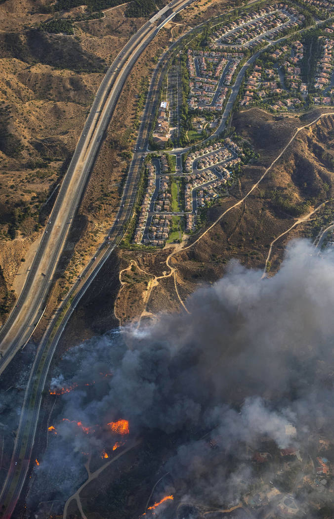 A wildfire moves closer to North Tustin homes along the 261 freeway in Tustin, Calif., Monday, Oct. 9, 2017. Deadly wildfires whipped by powerful winds swept through California wine country Monday ...