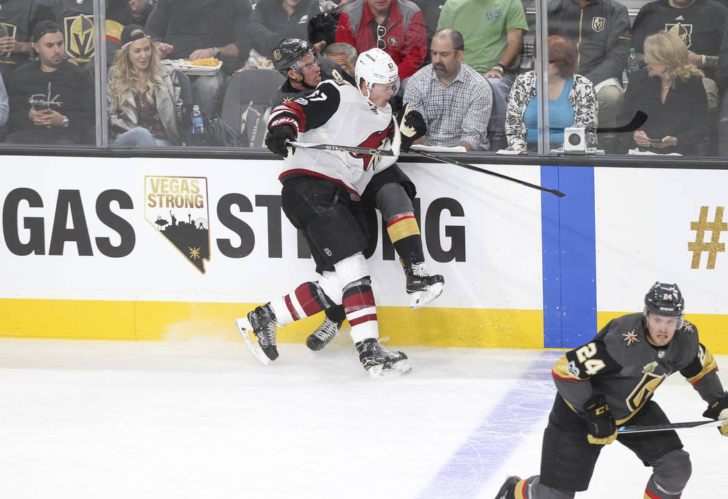 Vegas Golden Knights right wing Reilly Smith (19) is checked by Arizona Coyotes left wing Lawson Crouse (67) during the first period of an NHL hockey game between the Vegas Golden Knights and the ...