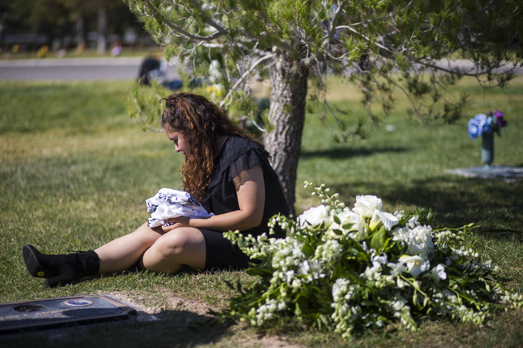 Sixteen-year-old Chantal Sosa rests next to the grave of her brother, Erick Silva, after his burial services at Davis Funeral Home & Memorial Park in Las Vegas on Thursday, Oct. 12, 2017. Silv ...