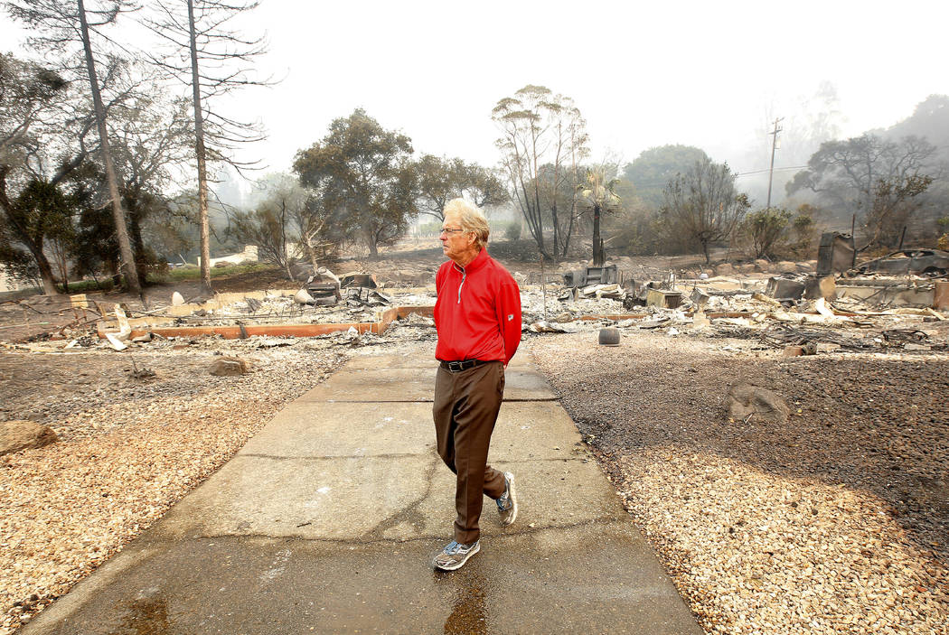 Mike Rippey walks away from the burned out remains of his parents home at the Silverado Resort, Tuesday, Oct. 10, 2017, in Napa, Calif. Charles Rippey, 100 and his wife Sara, 98, died when wind wh ...