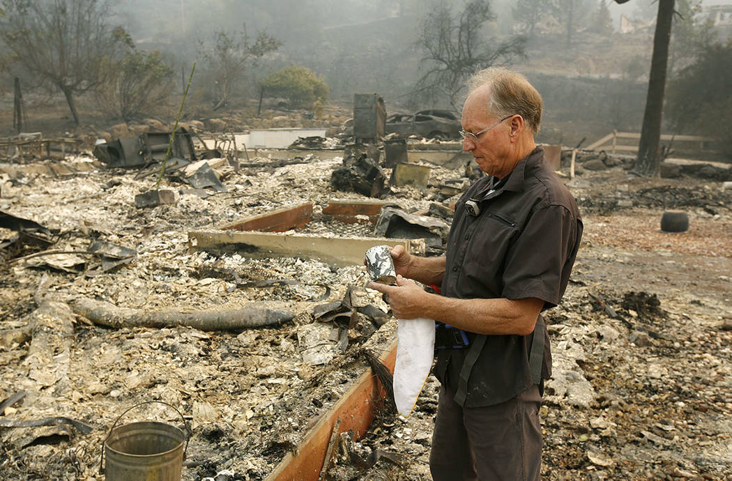 Chuck Rippey looks over a cup found in the burned out remains of his parent's home at the Silverado Resort, Tuesday, Oct. 10, 2017, in Napa, Calif. Charles Rippey, 100 and his wife Sara, 98, died  ...